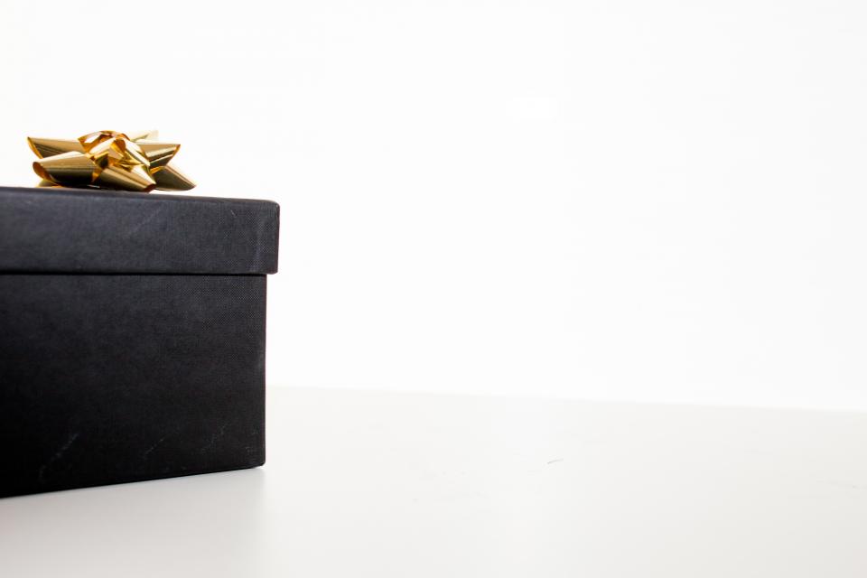 A black gift box with a gold bow on a white table