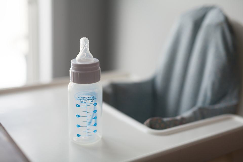 A baby bottle standing on a high chair tray
